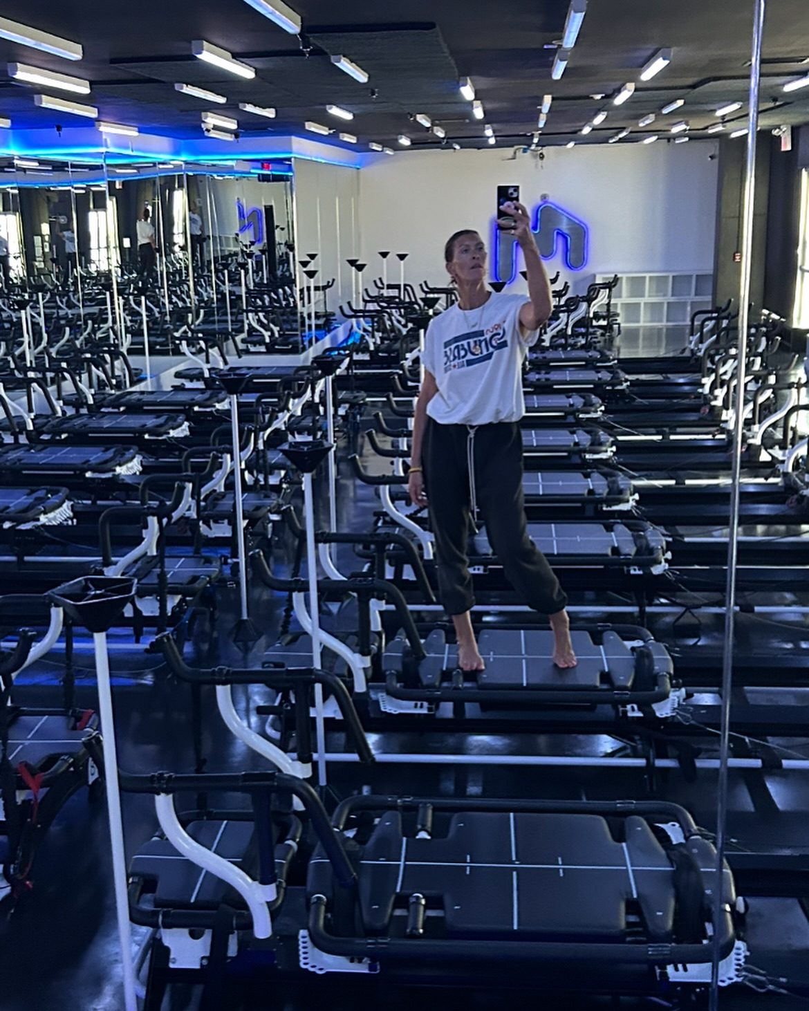 Sam standing on a Megaformer among rows of machines at the studio