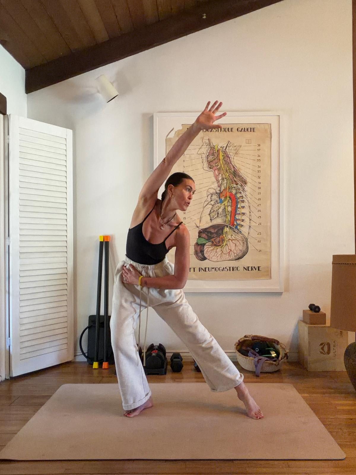 Sam mid side-stretch on a mat at home, one arm reaching overhead