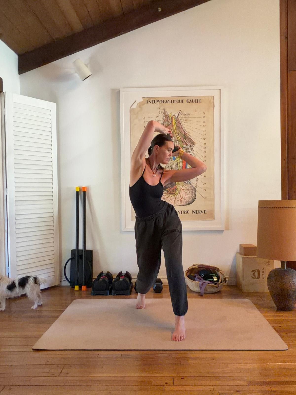 Sam mid-rotation on a mat at home, arms overhead