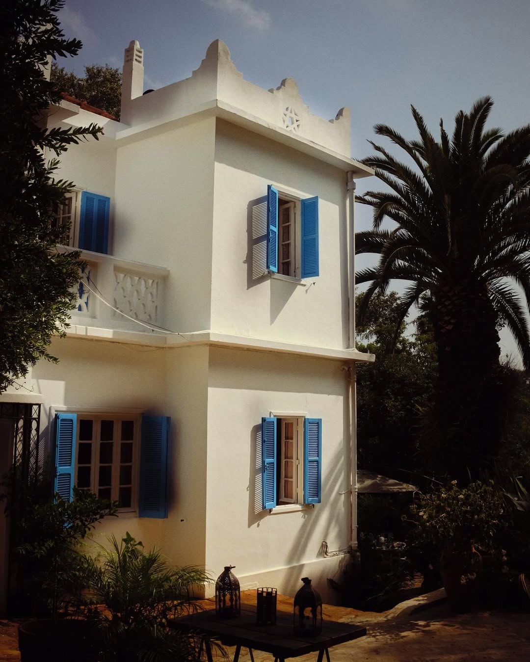 Dar Sinclair villa in Tangier — white walls, blue shutters, palm trees